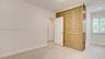 Neutral interior space featuring wood-finish flooring, louvered closet doors, and a window with white casing