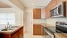 Kitchen featuring wood-finish cabinetry, stone-texture countertops, a mosaic tile backsplash, and stainless steel appliances