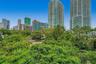 Urban landscape featuring high-rise buildings, mature tropical trees, and manicured greenery