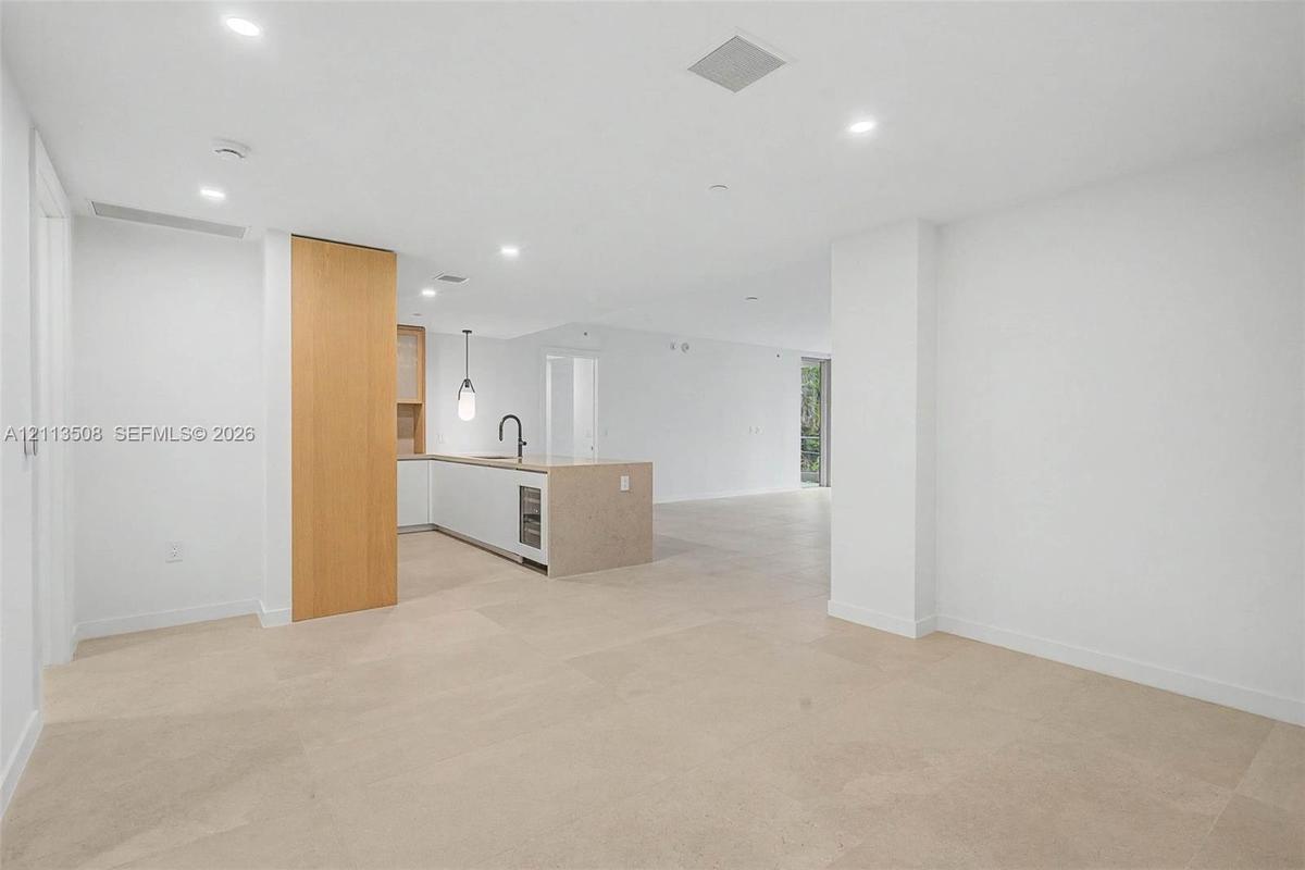Open-concept interior featuring large-format tile flooring, recessed ceiling lighting, a kitchen island with a stone-finish countertop, integrated und