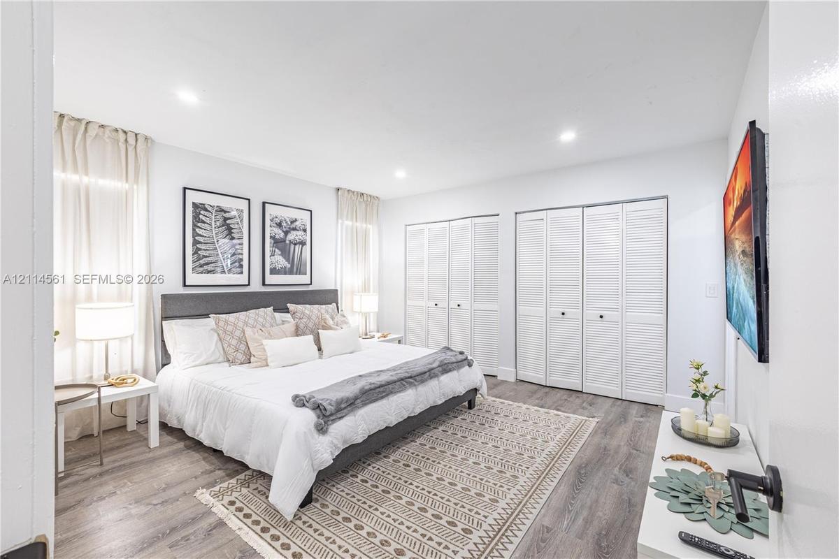 Wood-finish flooring, recessed lighting, and double-closet storage featuring white louvered doors