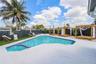 In-ground pool featuring a tile-accented spa, light-toned stone pool deck, artificial turf, and a full-perimeter privacy fence