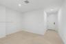 Neutral interior featuring light-toned flooring, recessed lighting, and a solid-core door with matte black hardware