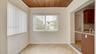 Wood-plank ceiling, neutral tile flooring, and sliding windows with vertical blinds