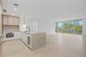 Kitchen featuring stone countertops, a waterfall-edge island, built-in beverage refrigerator, matte black faucet, and large-format tile flooring