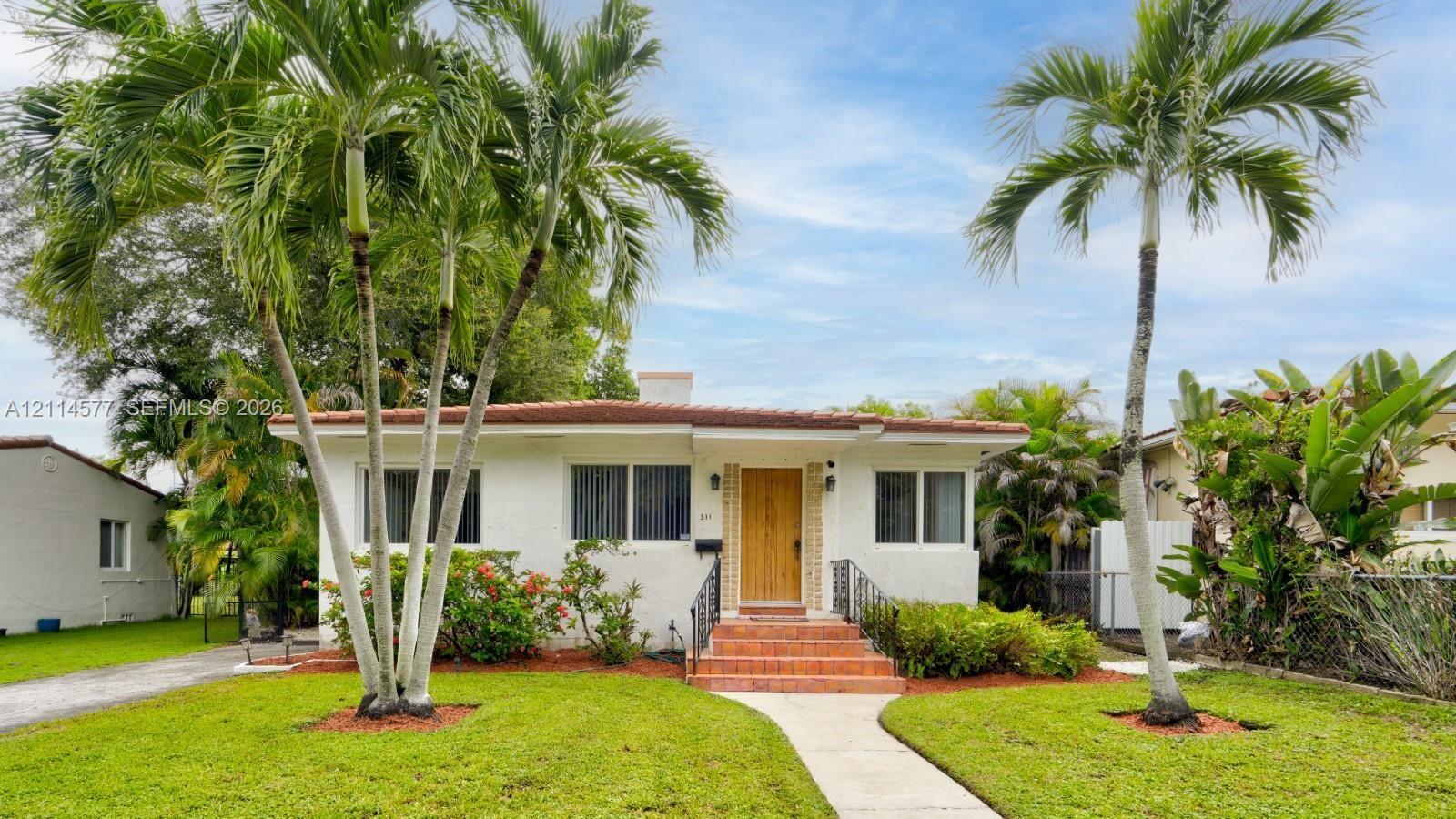 Single-story exterior featuring white stucco finish, tile roof, natural wood-finish front door, and tiled entryway steps with metal handrails