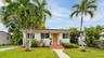 Single-story exterior featuring white stucco finish, tile roof, natural wood-finish front door, and tiled entryway steps with metal handrails