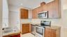 Kitchen featuring flat-panel wood-finish cabinetry, stone-surface countertops, textured stone backsplash, stainless steel appliances, and a double-bas