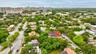Aerial perspective of a residential property featuring a hipped roof, mature canopy trees, and established landscaping within a dense urban corridor