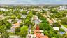 Aerial perspective featuring mature trees, paved streets, and residential density in the surrounding area