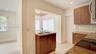 Kitchen featuring wood-finish cabinetry, stone-texture countertops, a dual-basin stainless steel sink, tiled backsplash, and light-toned wood-finish f