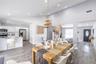 Vaulted ceilings, open-concept kitchen with white cabinetry and stainless steel appliances, wood-finish flooring, and natural-textured pendant lightin