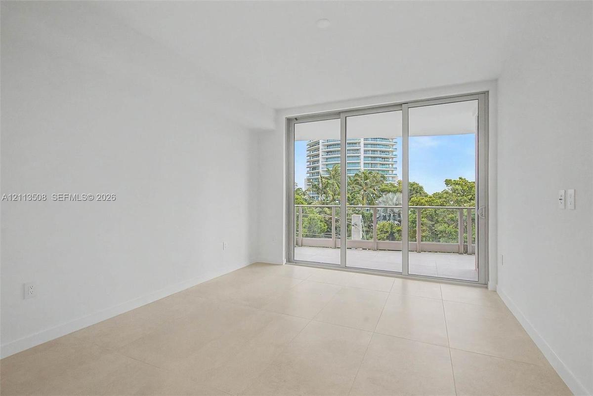 Neutral-toned tile flooring, floor-to-ceiling glass sliding doors, and a private balcony with metal railing
