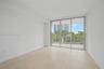 Neutral-toned tile flooring, floor-to-ceiling glass sliding doors, and a private balcony with metal railing