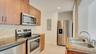 Kitchen featuring wood-finish cabinetry, stone-texture backsplash, stainless steel appliances, and solid-surface countertops with a dual-basin undermo