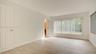 Neutral-toned interior featuring wood-finish flooring, six-panel doors, and large windows with vertical blinds