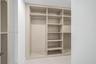Custom built-in storage featuring integrated shelving, vertical partitions, and horizontal hanging rods with a neutral finish