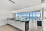 Kitchen featuring a central island with a dark stone countertop, integrated glass backsplash, white cabinetry with metal hardware, floor-to-ceiling wi