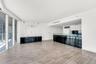 Open-concept floor plan featuring wood-finish flooring, floor-to-ceiling glass wall, built-in black lacquer cabinetry, and a kitchen island with a gla