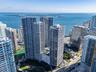 High-rise residential towers featuring glass-curtain facades, set along a coastal waterfront with proximity to a public park