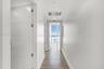 Hallway featuring horizontal-panel interior doors, light wood-finish flooring, and floor-to-ceiling windows with coastal scenery