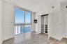 Floor-to-ceiling windows featuring expansive coastal scenery, wood-finish flooring, and built-in closet organization with shelving