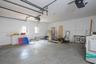Attached garage featuring white built-in cabinetry, dual wall-mounted garage door openers, fluorescent lighting, and two windows