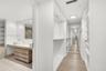 Walk-in closet featuring white built-in shelving, full-length mirror, and wood-finish flooring, accompanied by a bathroom with a dual-vessel sink vani