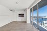 Floor-to-ceiling glass sliding doors, private balcony with metal railing, wood-finish flooring, and minimalist integrated wall cabinetry