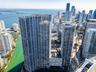 Aerial perspective featuring glass-facade high-rise towers, a multi-level podium with an elevated swimming pool and terrace, and proximity to the wate