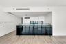 Kitchen featuring custom white cabinetry, integrated refrigerator, built-in microwave, minimalist glass-paneled island, and wood-finish flooring
