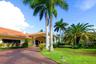 Exterior featuring a terracotta tile roof, brick paver driveway, covered entryway with classical columns, and mature palm trees