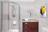 Curved glass shower enclosure with a handheld shower head and wall-mounted seat, complemented by a dark wood vanity, stone-finish countertop, and inte
