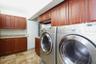 Laundry room featuring raised-panel wood cabinetry, stone-finish countertops, tile flooring, and crown molding