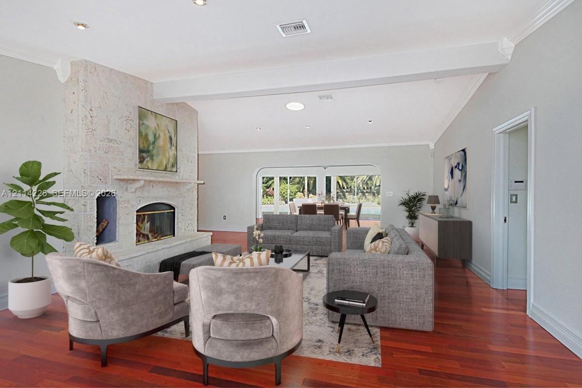 Living area featuring a floor-to-ceiling stone fireplace, wood-finish flooring, vaulted ceilings with recessed lighting, and arched patio access