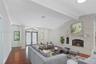 Living area featuring wood-finish flooring, vaulted ceilings with structural beams, floor-to-ceiling stone-clad fireplace with mantel, and decorative 