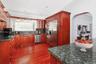Kitchen featuring rich wood cabinetry, stone countertops, stainless steel appliances, recessed lighting, and wood-finish flooring