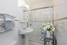 Pedestal sink, wall-mounted medicine cabinet, white tile surround with decorative inlays, and glass-enclosed shower featuring a handheld fixture