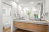 Floating wood-finish vanity with dual integrated sinks, stone-finish countertop, full-width vanity mirror, and wood-finish flooring