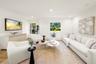 Neutral-toned interior space featuring light wood-finish flooring, recessed lighting, and multiple windows providing natural illumination