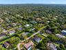 Aerial perspective of a residential neighborhood featuring mature tree canopies, paved street infrastructure, and multiple properties with private swi