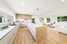 Kitchen featuring flat-panel cabinetry, a central island with stone-finish surfaces, integrated stainless steel double wall ovens, recessed lighting, 