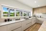 Modern kitchen featuring light-toned cabinetry, wood-finish flooring, stone-textured countertops and backsplash, and an integrated undermount sink wit