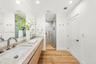 Floating dual-sink vanity with stone-finish countertop, wood-finish cabinetry, frameless glass walk-in shower, and wood-finish flooring