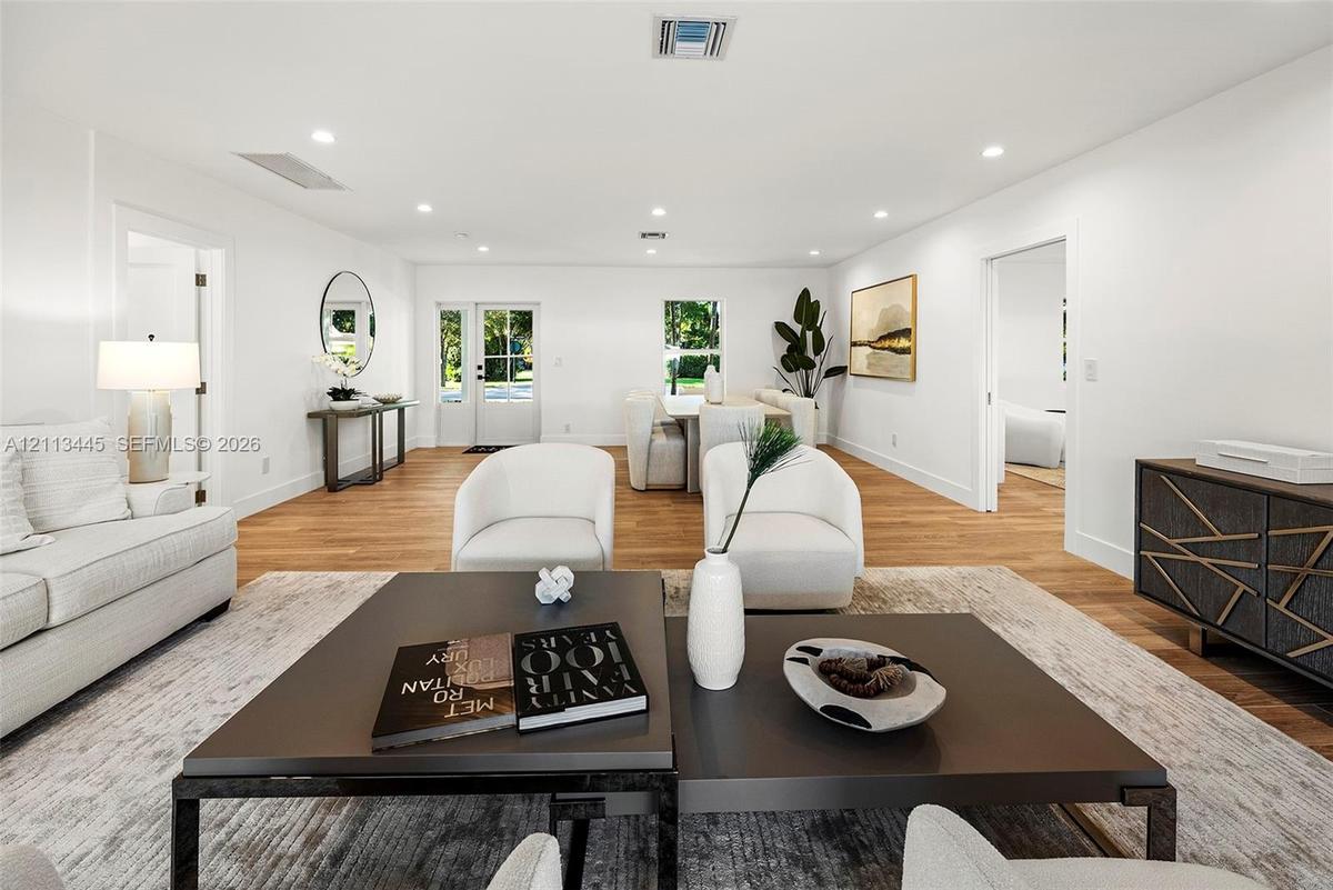 Open-concept interior featuring wood-finish flooring, recessed lighting, and a glass-paneled entry door