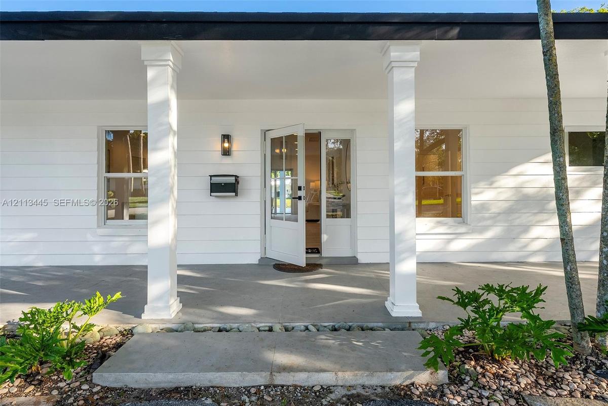 Covered front porch featuring white horizontal siding, square columns, a concrete foundation, and a glass-paneled entry door
