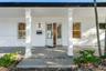 Covered front porch featuring white horizontal siding, square columns, a concrete foundation, and a glass-paneled entry door
