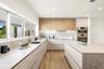 Kitchen featuring flat-panel cabinetry in matte and light wood finishes, stone-composite countertops, built-in stainless steel double ovens, and wood-