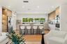 Modern kitchen featuring light wood-finish cabinetry, a central island with a solid-surface countertop, stainless steel appliances, stone-look backspl