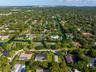Aerial perspective featuring residential lots with canal frontage, mature trees, and dense foliage within a suburban setting